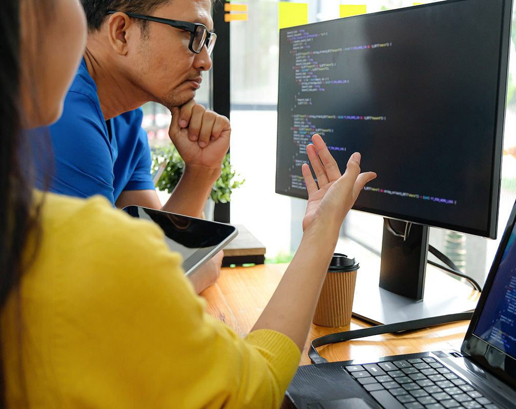 Female programmer wearing yellow shirts pointing at computer
